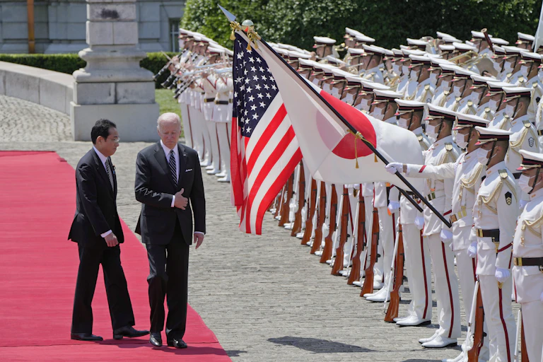 Two men in dark suits walk down a red carpet next to guards holding aloft the flags of JaEugene Hoshiko - Pool/Getty Imagespan and the United States.