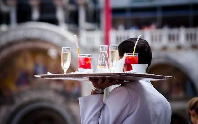 A man balances a tray of drinks in a restaurant.