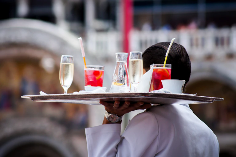 A man balances a tray of drinks in a restaurant.