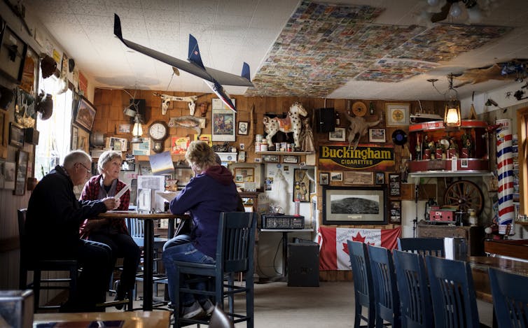 Four middle-aged people sit at a tall table in a diner-type restaurant.
