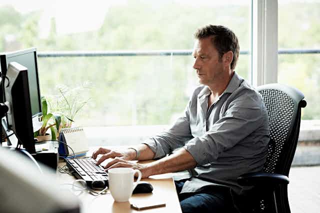 A man sitting at his desk working on his computer.