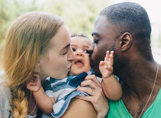 woman and man kiss opposite cheeks of a baby