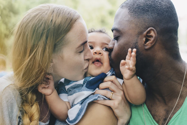 woman and man kiss opposite cheeks of a baby