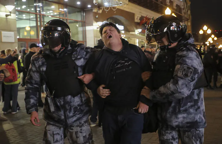 Russian police in riot gear holding an anti-war protester in Moscow, September 2022.