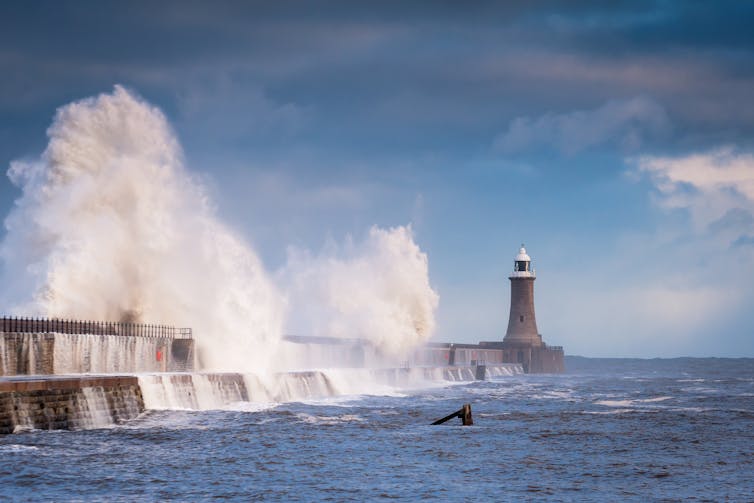 A large wave crashing against a breakwater.