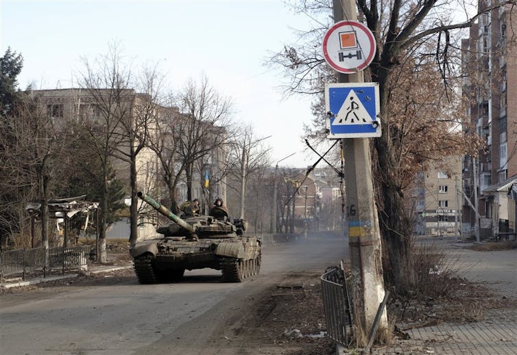 A Ukrainian tank drives down a tree-lined street in Bakhmut, eastern Ukraine.