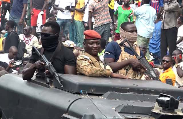 Trois hommes armés à bord d'un char militaire au Burkina Faso. 