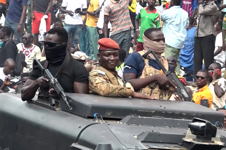 Trois hommes armés à bord d'un char militaire au Burkina Faso.