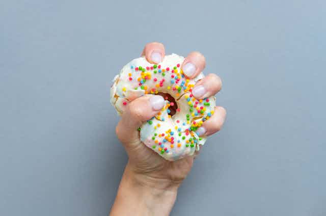 A hand squeezing a doughnut.