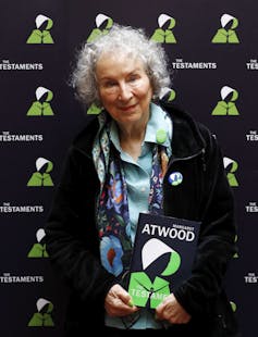 A woman with grey hair carries a book.