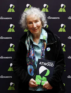 A woman with grey hair carries a book.