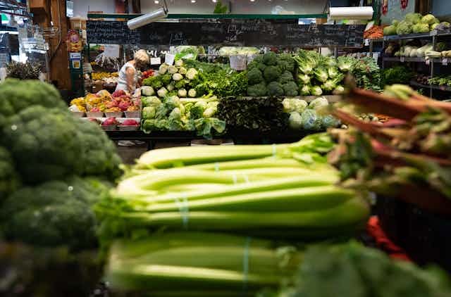 The produce section of a supermarket, with heads of celery in the foreground.