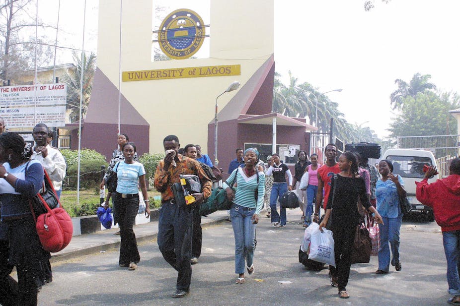 A group of young men and women carrying bags out of a university building.