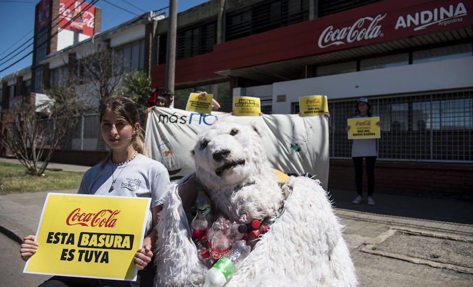 militante et ourse en peluche devant une usine coca cola