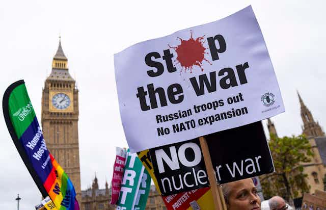 Anti-war protesters outside the UK parliament holding banners calling for anend to war and to Nato expansion.