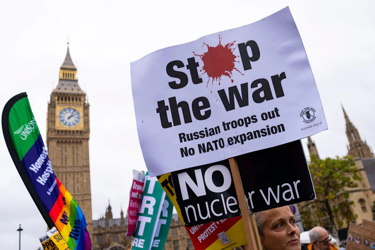 Anti-war protesters outside the UK parliament holding banners calling for anend to war and to Nato expansion.