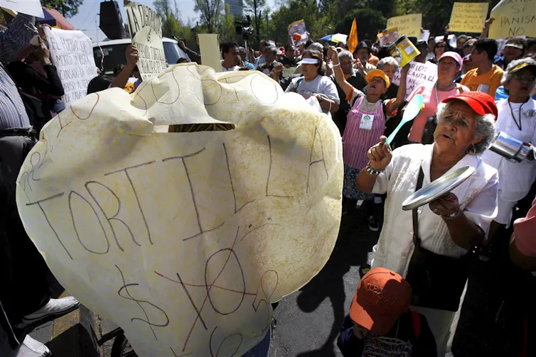 A protestor holds up a tortilla with a protest slogan written on it.