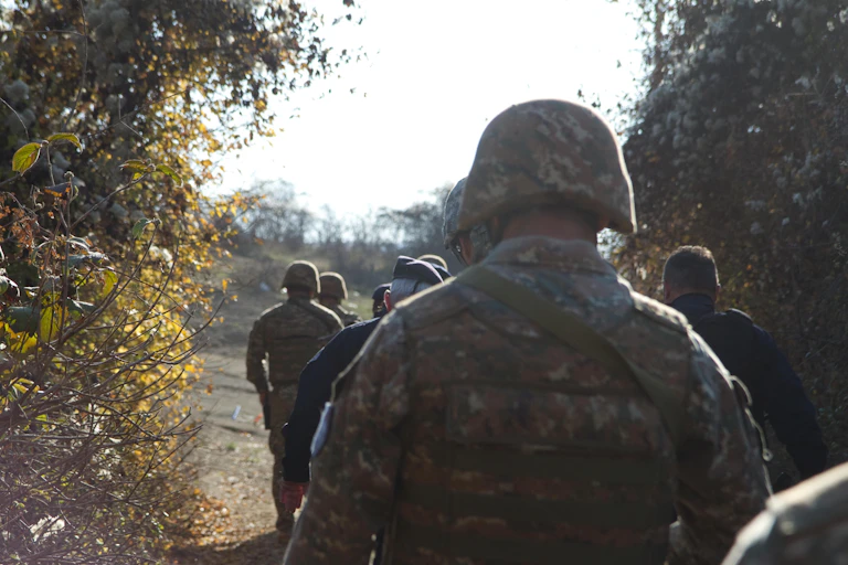 Soldiers wearing camouflage patrol a lane.