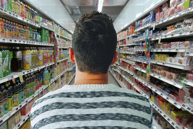 Homme hésitant dans un rayon de supermarché