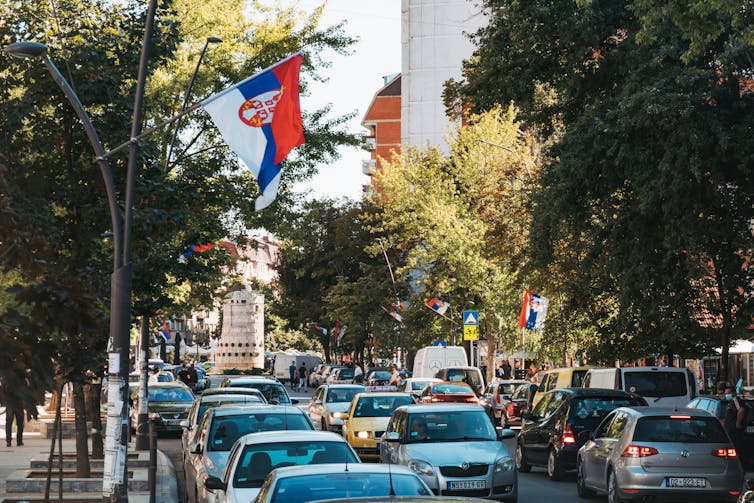 На путу пуном аутомобила вијоре се српске заставе.