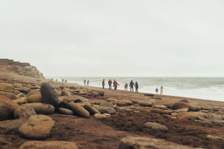 People walking along a rocky beach at Bridport