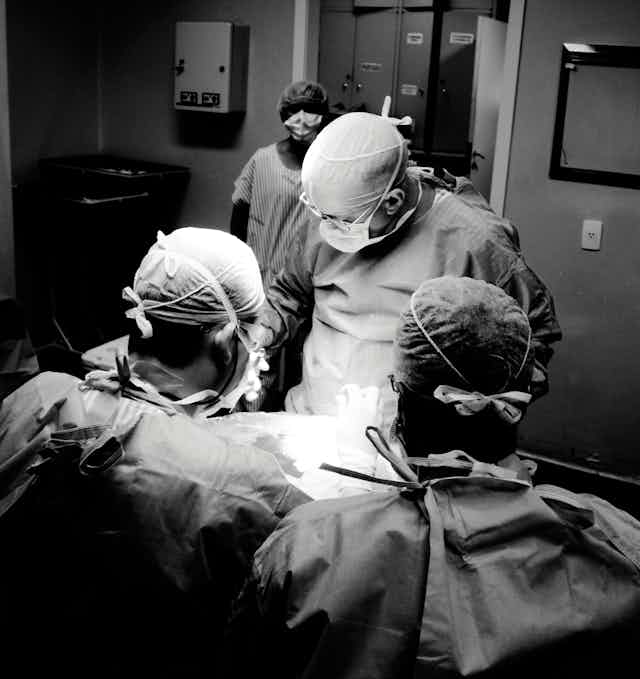 Cirujanos observan un cuerpo en la mesa de operaciones.