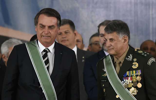 Brailian presidewnt Jair Bolsonaro in a suit with a sash and General General Edson Leal Pujol in military uniform with a sash.
