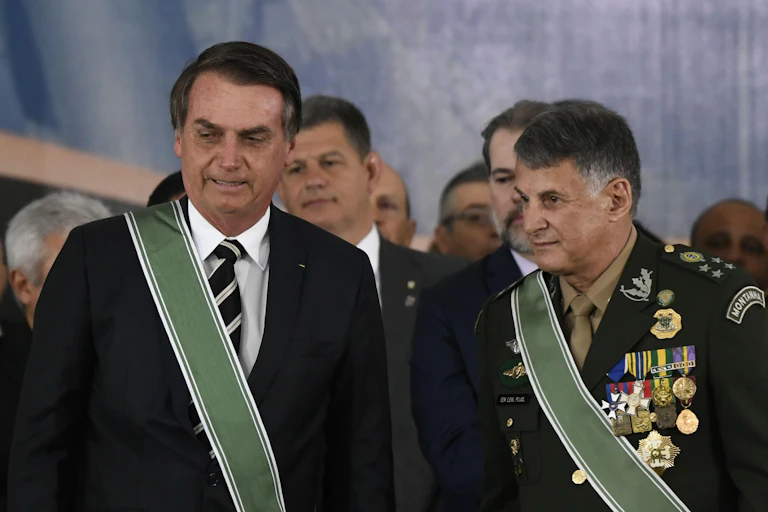 Brailian presidewnt Jair Bolsonaro in a suit with a sash and General General Edson Leal Pujol in military uniform with a sash.