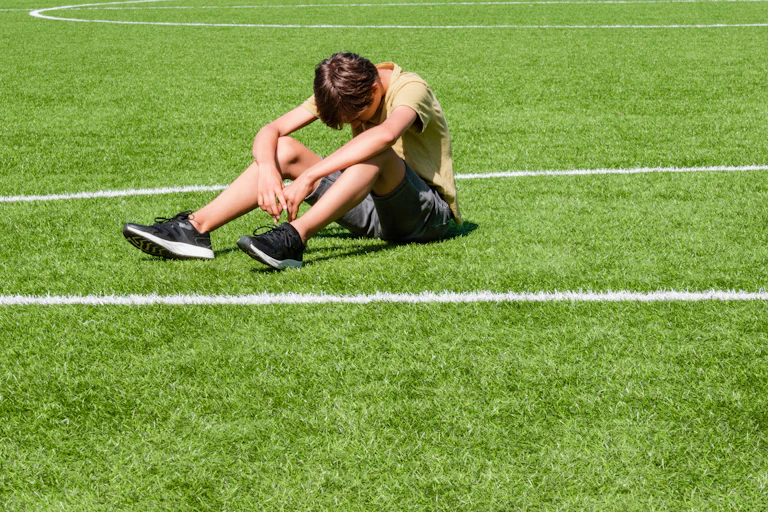 Niño abatido en un campo de fútbol.