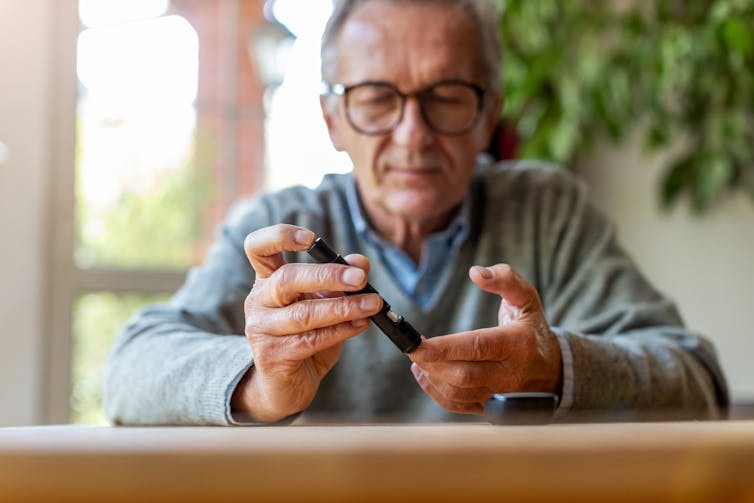 A man pricks his finger with blood sugar measuring device.