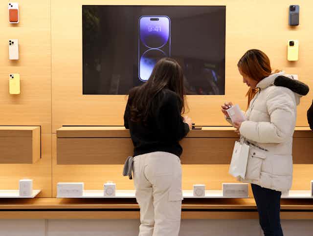 Two shoppers look at new phones in an Apple store