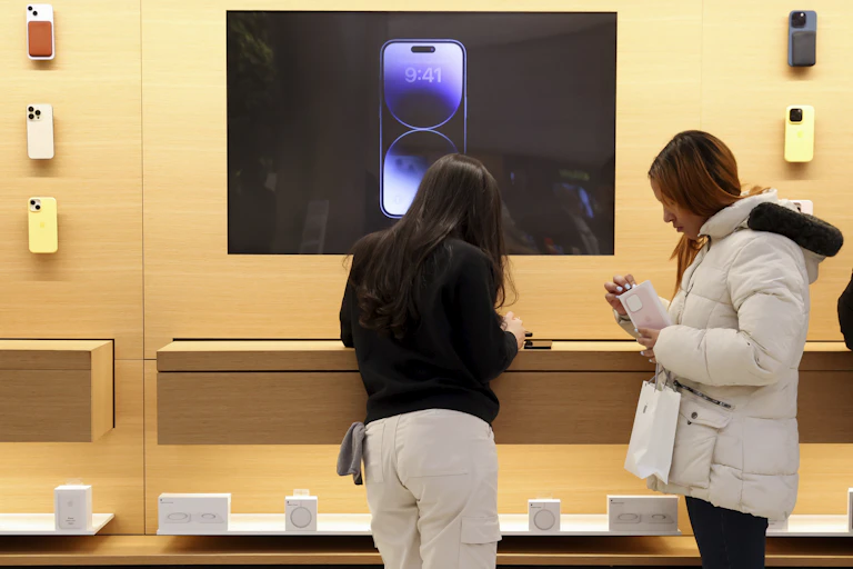 Two shoppers look at new phones in an Apple store