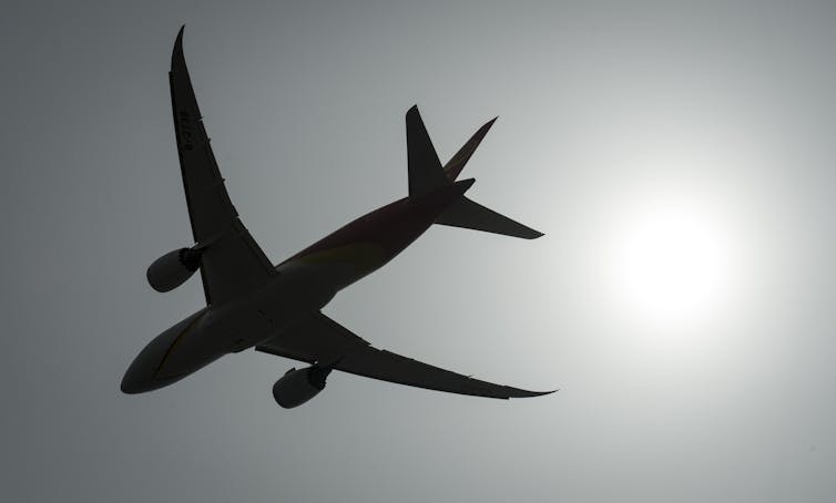 A plane silhouetted against a gray sky