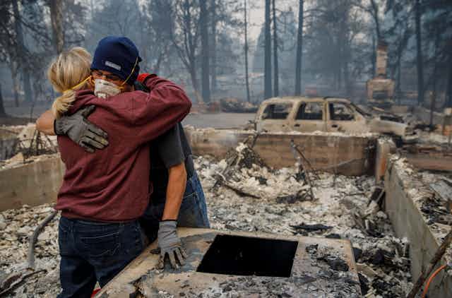 A woman hugs a man in the burned out remains of a home in Paradise, California.
