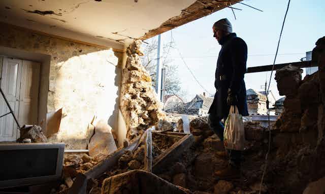 Man walking though rubble of a destroyed house in the city of Kherson after heavy Russian shelling