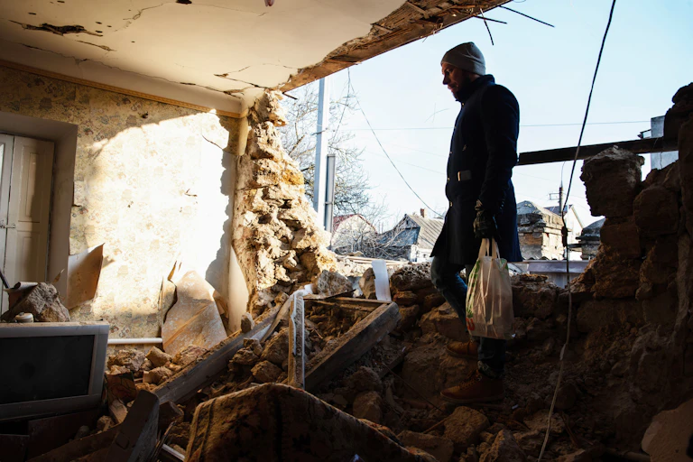 Man walking though rubble of a destroyed house in the city of Kherson after heavy Russian shelling