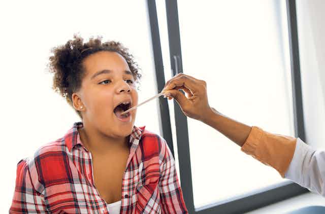 young person getting throat checked by health worker