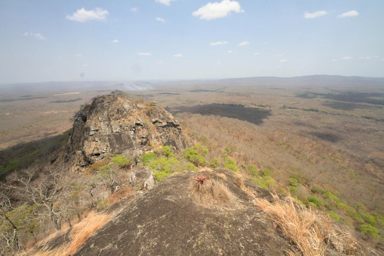 A view from above of a landscape, with two protruding hills overlooking rocks and trees