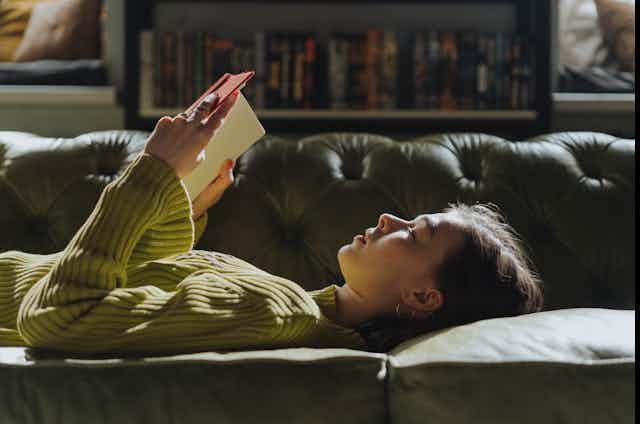 woman reading on a couch with bookshelves in background