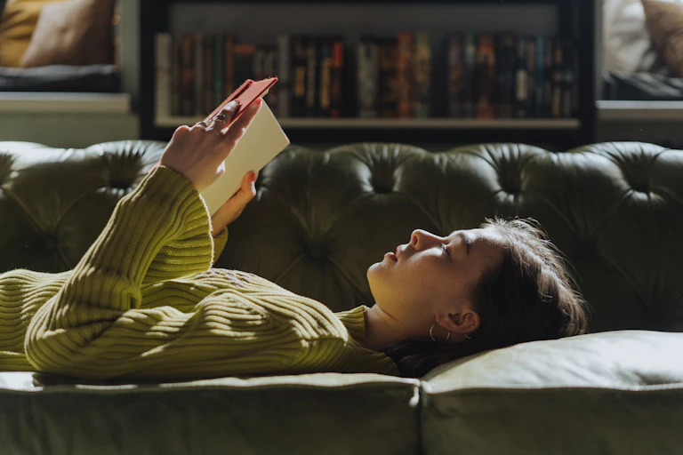 woman reading on a couch with bookshelves in background
