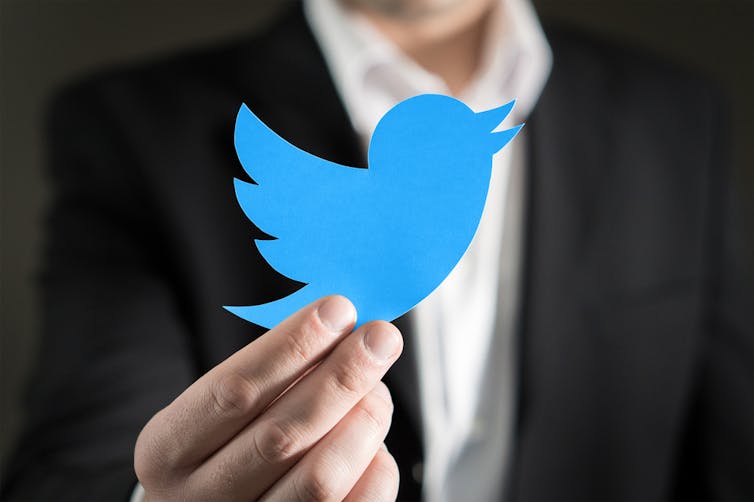 Businessman holding up a Twitter icon