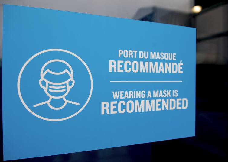 A blue sign reading 'wearing a mask is recommended,' in French and English