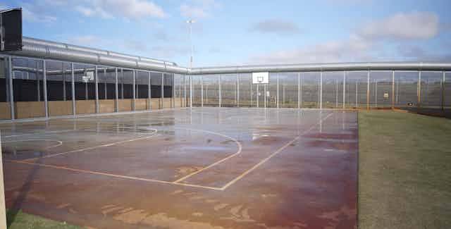 A fenced off outdoor area with a basketball court.