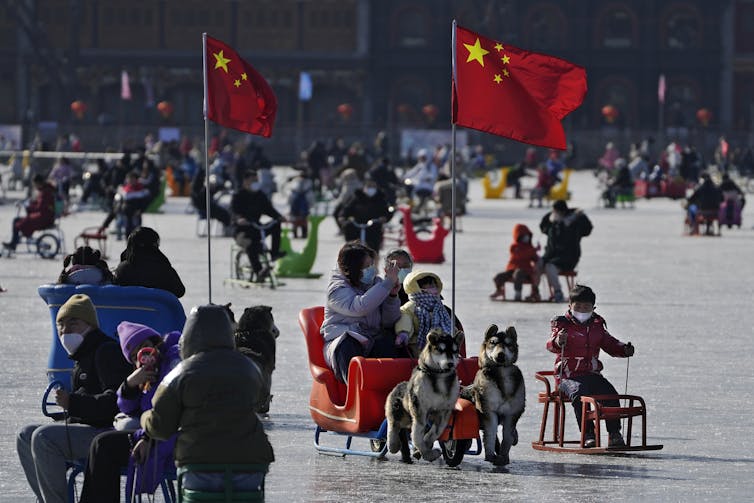 People on ice sleds in frozen lake in China. Chinese flags