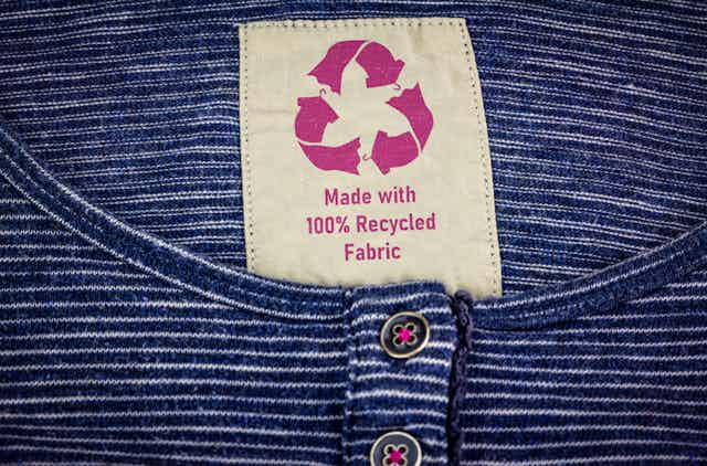 A tag on a blue striped shirt reads 'made with 100% recycled fabric'