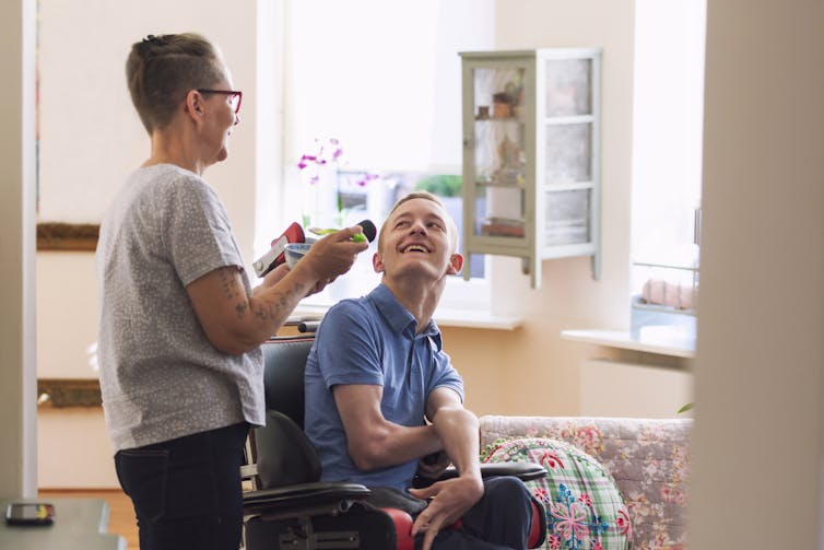 person with cerebral palsy sits in wheelchair while carer holds bowl and spoon