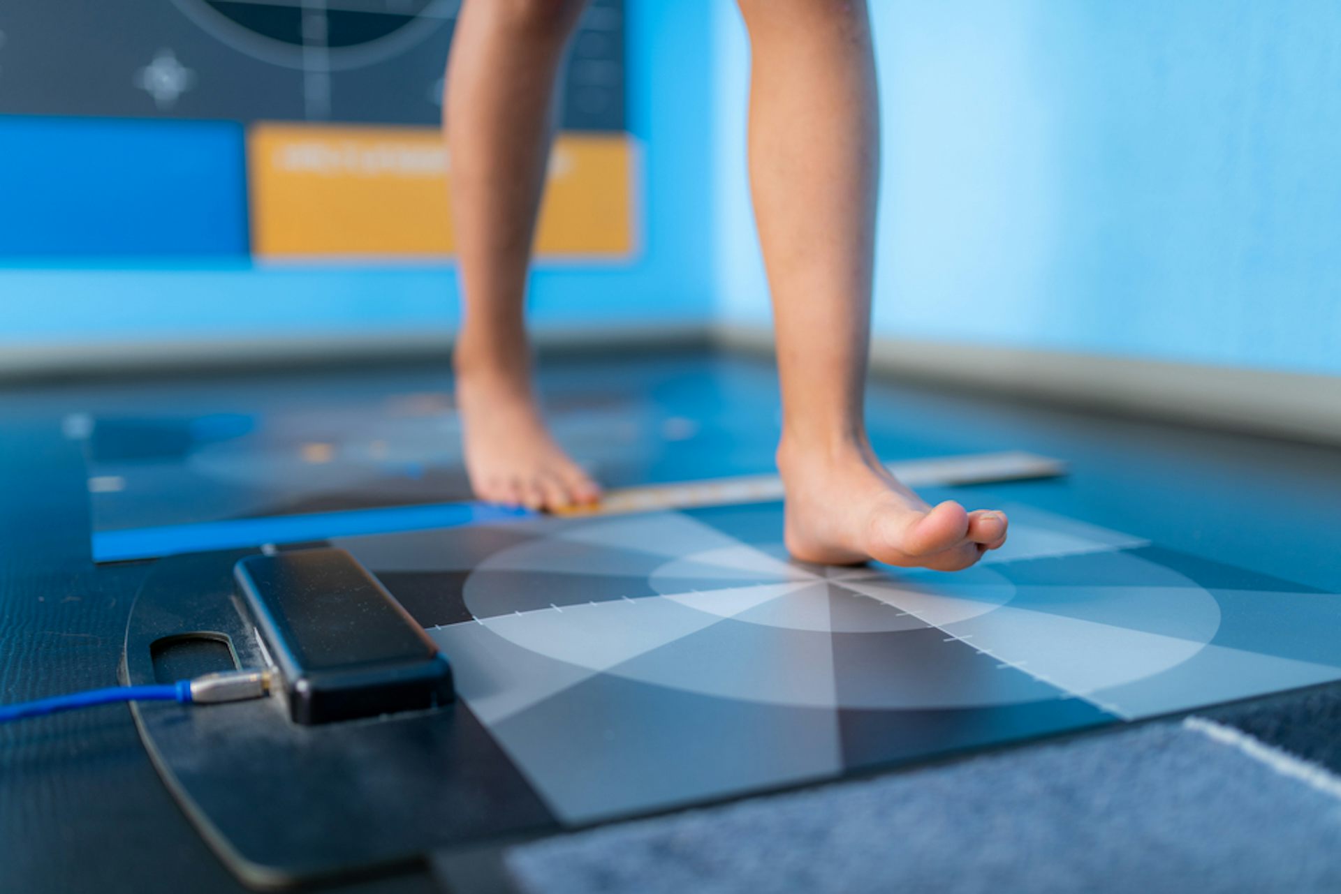 Two naked feet taking a step on a blue gait measuring plate in a laboratory
