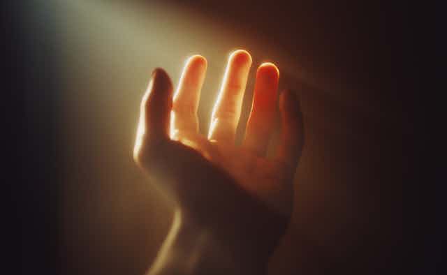 A human hand with bright illumination on a sepia background