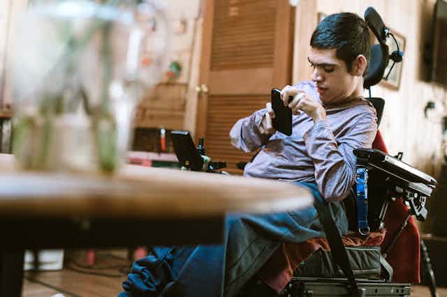 Man in wheelchair uses mobile phone