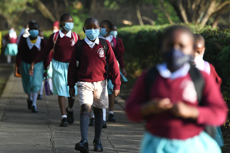 Boys and girls in school uniform and wearing face masks walking.